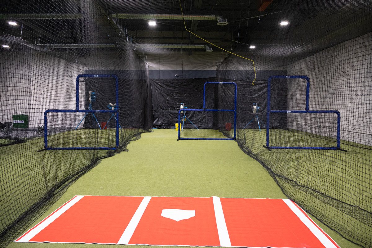 View down the batting cage lanes, showing protective netting and indoor turf